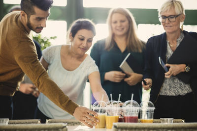 Business people picking up disposable cups of fresh juice in office