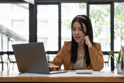 Businesswoman using laptop while sitting on table