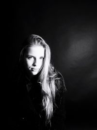 Portrait of beautiful young woman against black background