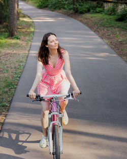 Portrait of young woman riding bicycle on road