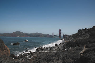 Suspension bridge over sea against clear sky