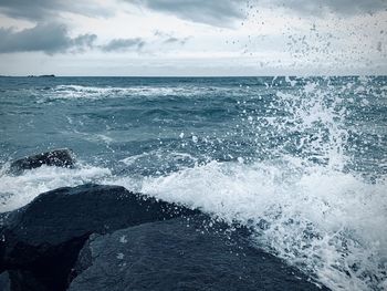 Scenic view of sea waves splashing against sky