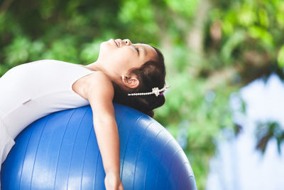 Smiling girl exercising on fitness ball