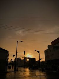 Street lights in city against sky during sunset