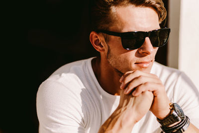 Portrait of young man wearing sunglasses against black background