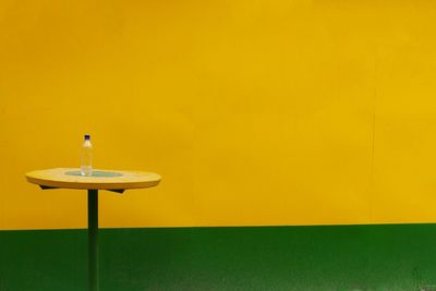 Water bottle on table against painted wall