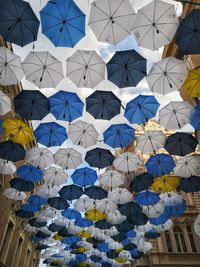 Low angle view of multi colored umbrellas hanging in city against sky