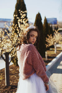 Portrait of young woman standing against clear sky