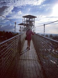 Rear view of woman on railing against sky