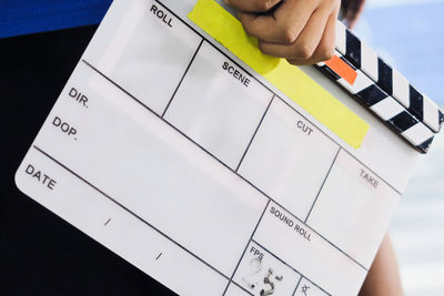 Midsection of man holding film slate while standing outdoors