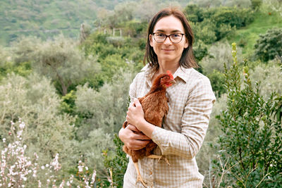 Woman holding brown hen in her hands in the farm. free-grazing domestic hen on organic farm.