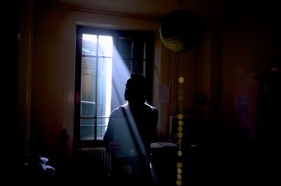 Man standing by window in darkroom