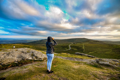 Side view of woman looking at landscape against cloudy sky