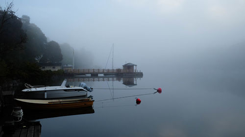 Sailboats moored on sea against sky