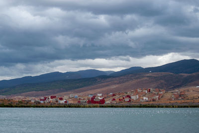 Scenic view of lake by buildings against sky