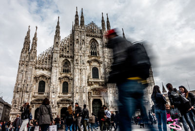 People in front of milan cathedral against cloudy sky