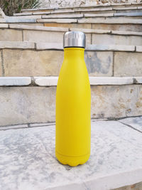 Yellow reusable steel bottle on stairs outdoor close up