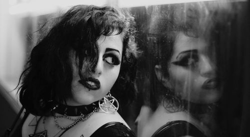 Close-up of young woman standing by mirror