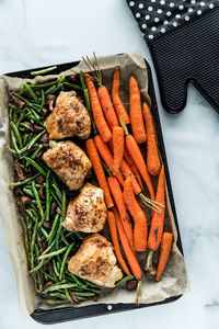 Top down view of a sheet pan filled with roasted chicken thighs and veggies.