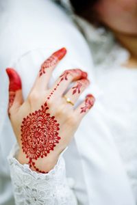 Midsection of groom by bride with henna tattoo