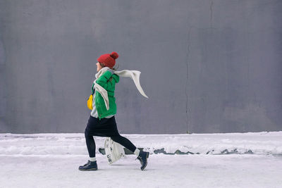 Side view of man standing against snow covered wall