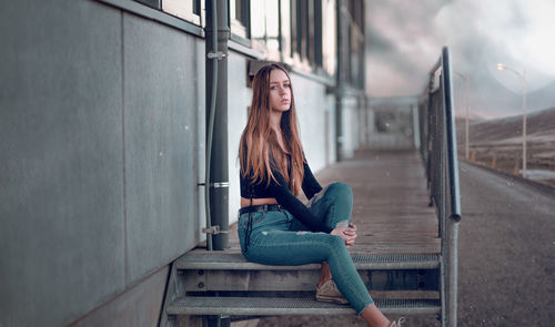 Young woman sitting on railing