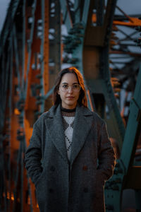 Portrait of young woman standing against wall