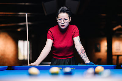 Portrait of young woman playing pool