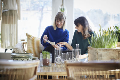 Smiling female owners discussing over documents at boutique