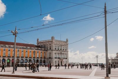 People in front of building against cloudy sky