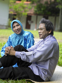 Happy couple sitting on grass in back yard