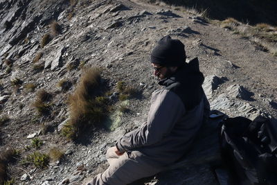 Rear view of man sitting on rock
