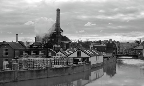 Buildings by river against sky in city