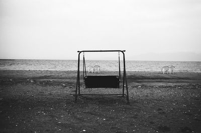 Swing on sand at beach against clear sky