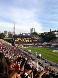 Crowd photographing city against sky