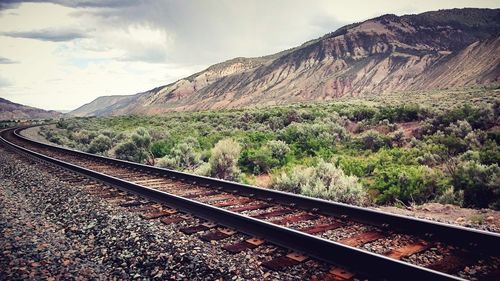 Railroad track by mountains against sky