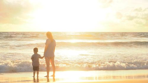 People standing on beach at sunset