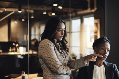 Businesswoman pointing while talking to female colleague at office