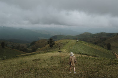 Rear view of woman standing on field against landscape