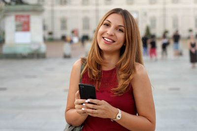 Portrait of smiling young woman using mobile phone