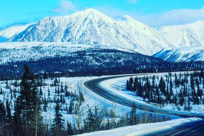 Snow covered road by mountains against sky