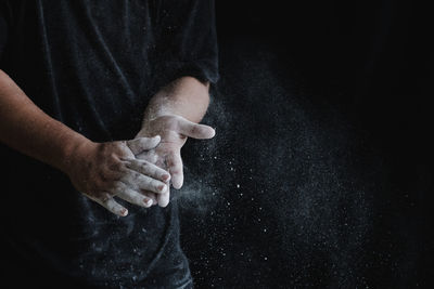 Close-up of man holding hands over black background