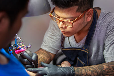 Close-up of tattoo artist tattooing in studio