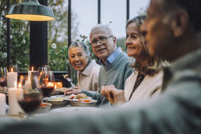 Male and female senior friends having food at dinner party