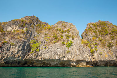 Rock formations by sea against clear sky