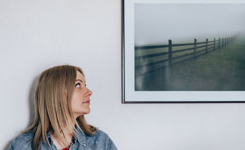 Woman looking at frame against wall