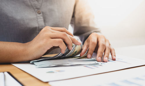 Midsection of woman counting money on table