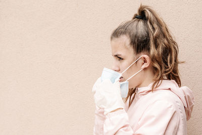 One blonde girl wearing latex gloves and face masks is showing the way she protects herself from coronavirus, bacterias, virus, fungus, etc. she removed mask to take clear breath. horizontal