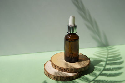 Cosmetic bottle with facial serum on a wooden podium. the concept of zero waste and ecology. 