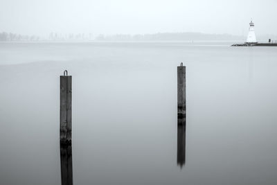 Wooden post in sea against sky